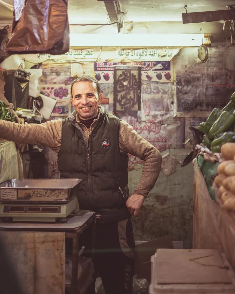Épicier marocain souriant derrière le comptoir de son épicerie de proximité
