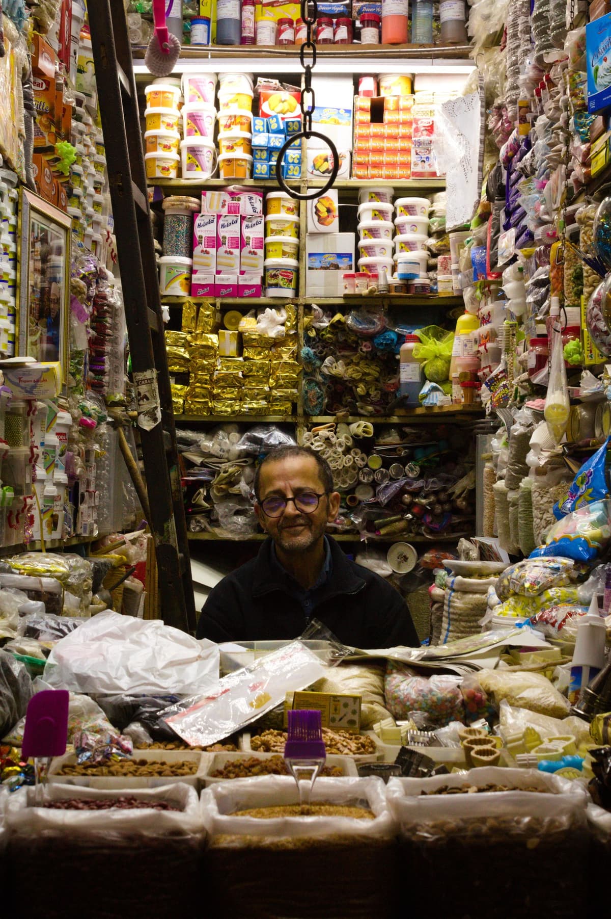 Épicier marocain au comptoir de son magasin bien achalandé